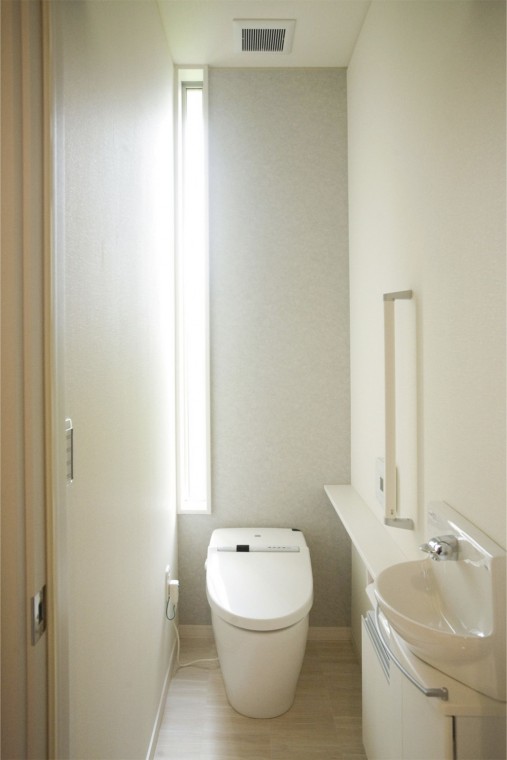 天井まである縦長窓とタンクレストイレが空間を広く感じさせ手摺を付け立ち座りの負担を軽減。